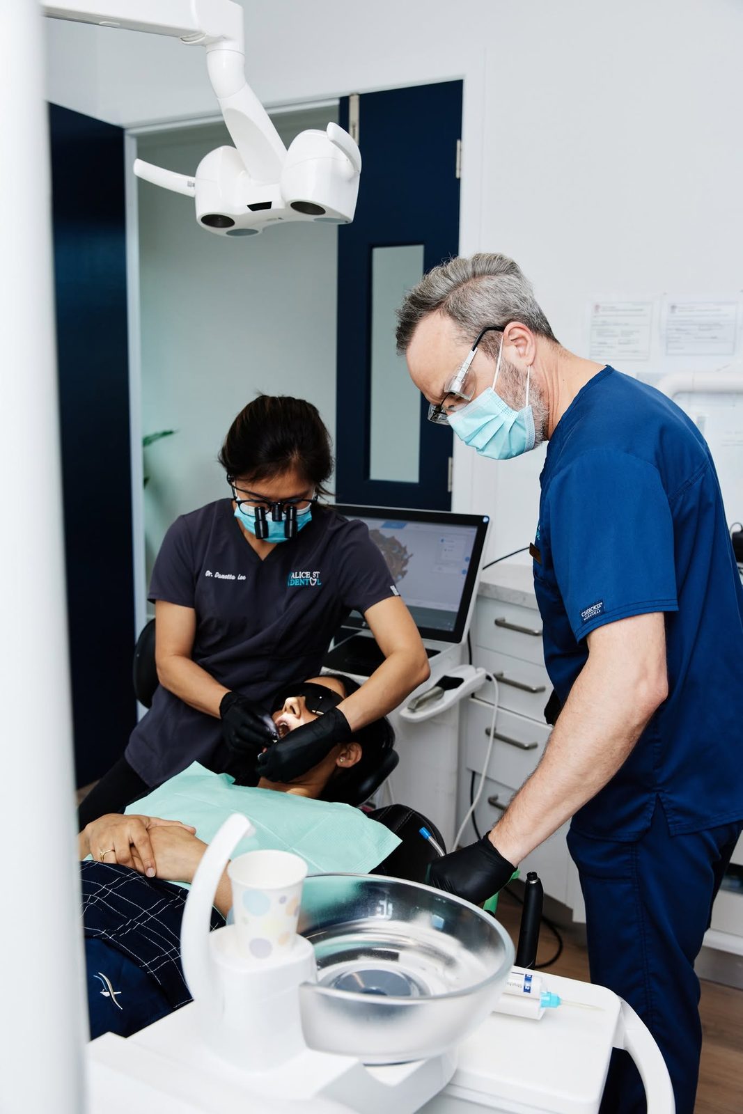 Dr Danetta Lee treating a patient while a colleague assists, with a digital scan on the screen